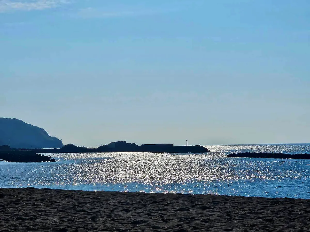 朝日を受けてきらめく鯨波の海と砂浜