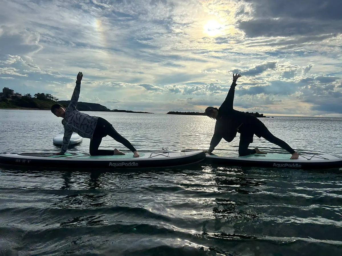 おだやかな海の上、SUPボードの上でヨガをする様子